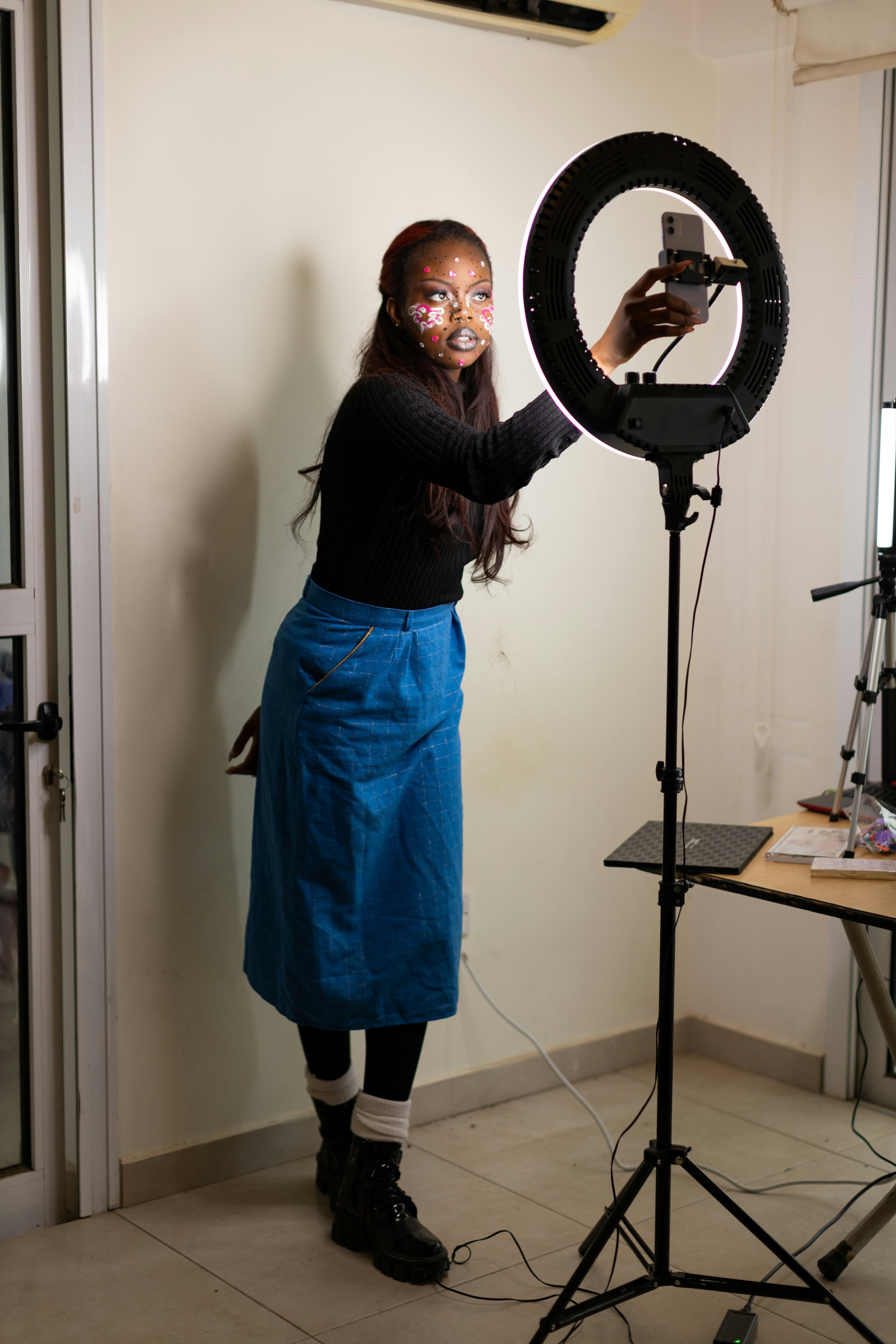 A creator with festival face gems filming with a ring light and phone
